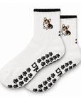 The Tri Color Corgi Grip Sock in white with a black cuff, embroidered tri-color corgi, and paw-shaped non-slip grips, laid flat on a white background