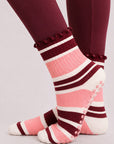 Pink and burgundy striped pilates grip socks worn with burgundy leggings, side view