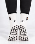 Back view of Black Cat Grip Socks on feet showing black paw print grips, almla logo and paw prints on the ankle