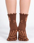 Model standing in a pair of The Doodle Grip Sock, front view showing the embroidered golden doodle on each ankle and paw-print grip soles with the Almla logo