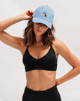 Woman in black activewear touching the brim of The Tri-Color Corgi Denim Hat