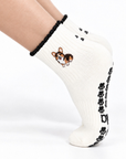 Side view close-up of a foot wearing the Tri-Color Corgi grip sock with black cuff, embroidered corgi design, and black paw print grip sole