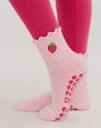 Side view of legs in pink leggings wearing pink strawberry women's grip socks for pilates with ruffle cuffs.