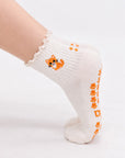 Model wearing The Orange Cat Grip Sock on pointed toes, side profile showing the paw-print grip soles and embroidered orange tabby cat