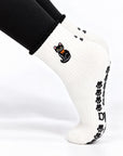 Black Cat Grip Sock worn on a pointed foot showing the embroidered black cat and paw prints on the back of the ankle