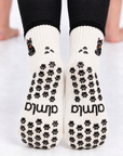 Close up of the soles of the Black Cat Grip Socks with black paw-shaped non-slip grips and almla logo