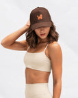 Woman in a cream matching set wearing The Goldendoodle Brown Hat, angled view
