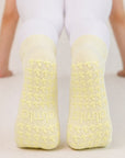 Non-slip soles of butter yellow grip socks with tonal flower grips and almla logo