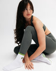Woman wearing a gray athletic outfit with white socks on a white background