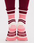 Pink and burgundy grip socks worn on feet positioned on toes showing the sole and grip pattern on burgundy leggings