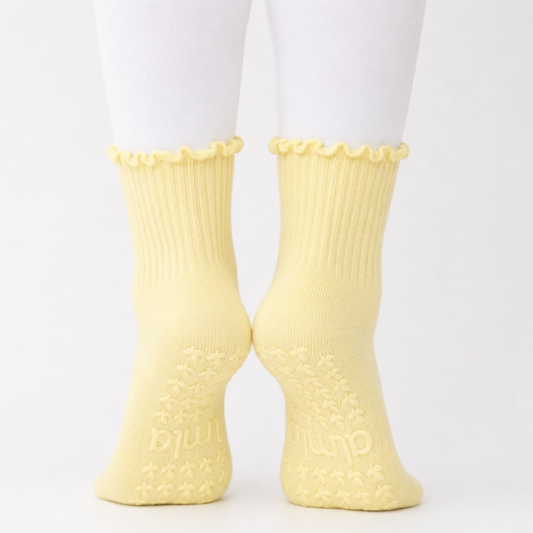 Butter yellow ribbed crew grip socks worn with white leggings, back view with grip soles