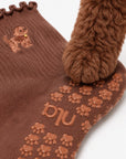 A real golden doodle's paw resting on the paw-print grip sole of The Doodle Grip Sock, showing the embroidered dog design on the cuff