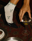 Martini grip socks styled with black stiletto heels and a martini at a cocktail bar