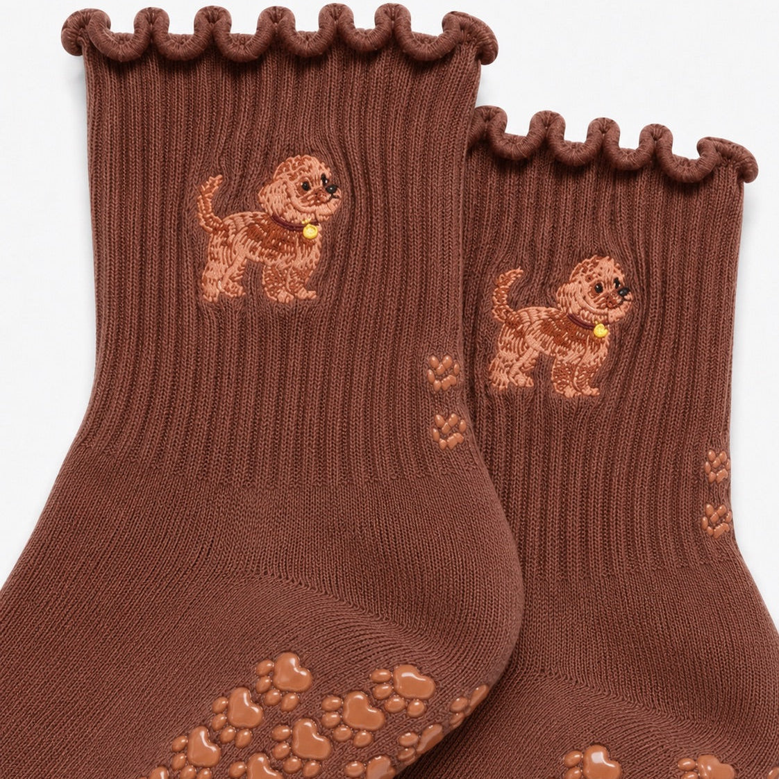 Close-up of The Doodle Grip Sock detailing the embroidered golden doodle design, ruffle cuff, and paw-shaped non-slip grip soles