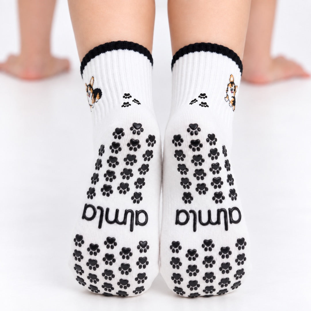 Back view of The Tri Color Corgi Grip Sock worn on both feet, showing the full paw-print grip pattern and Almla logo on the soles