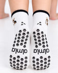 Back view of The Tri Color Corgi Grip Sock worn on both feet, showing the full paw-print grip pattern and Almla logo on the soles