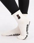 Side view of the Black Cat Grip Sock on foot showing the embroidered black cat, scalloped cuff and paw print grips