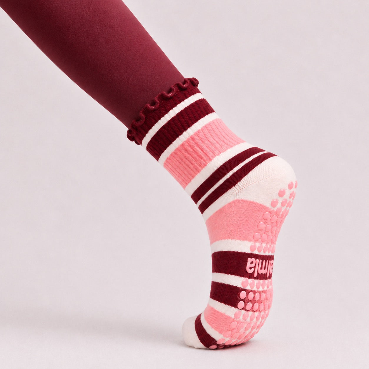 Close-up side view of a woman in plank wearing raspberry cream grip socks with non-slip sole