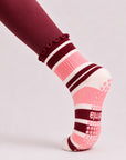 Close-up side view of a woman in plank wearing raspberry cream grip socks with non-slip sole