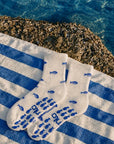 Pair of white fish-print cute pilates socks laid on a blue striped towel by the sea with blue fish grip soles.