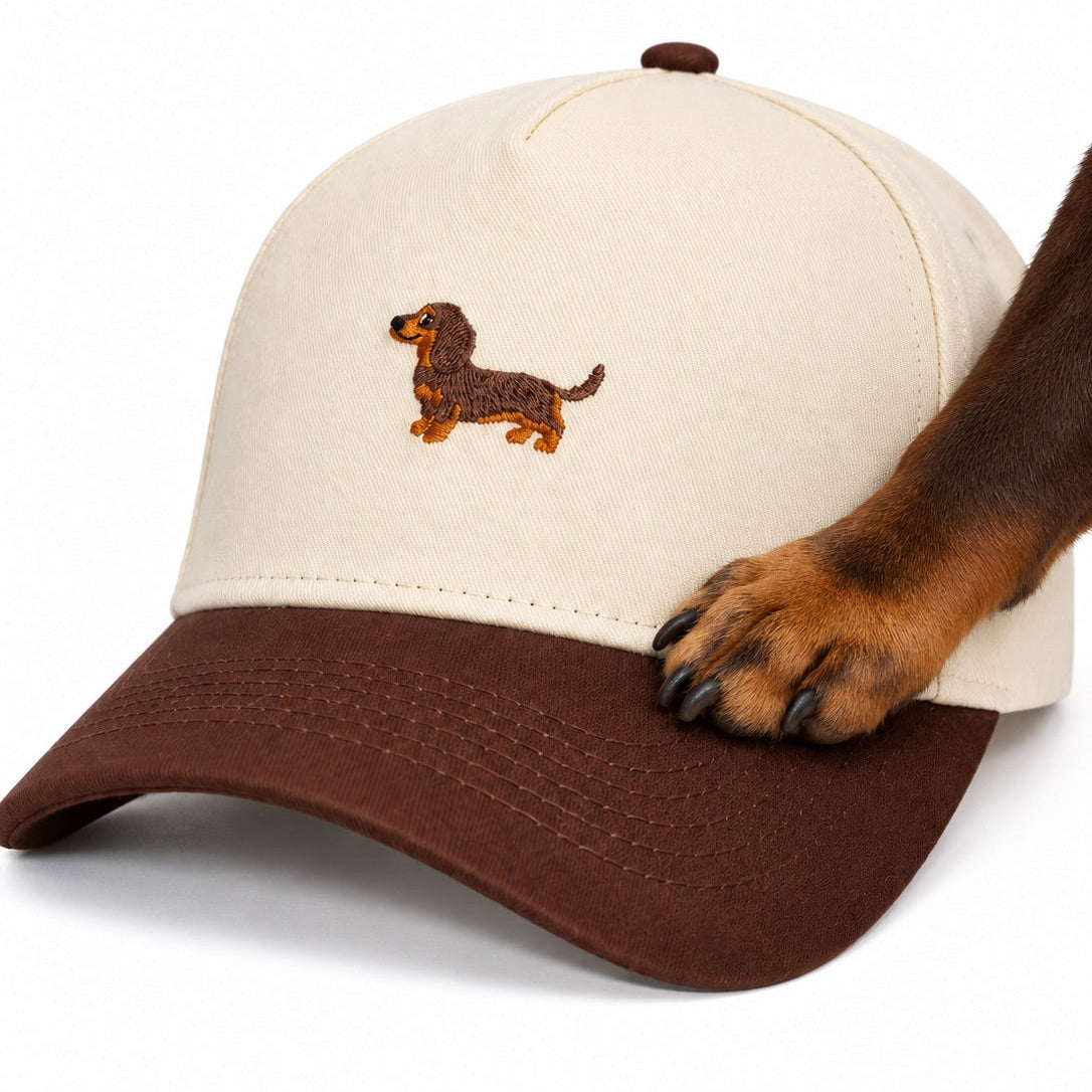 Dachshund paw resting on the brim of The Doxie Brown Hat, close up of the embroidered dachshund