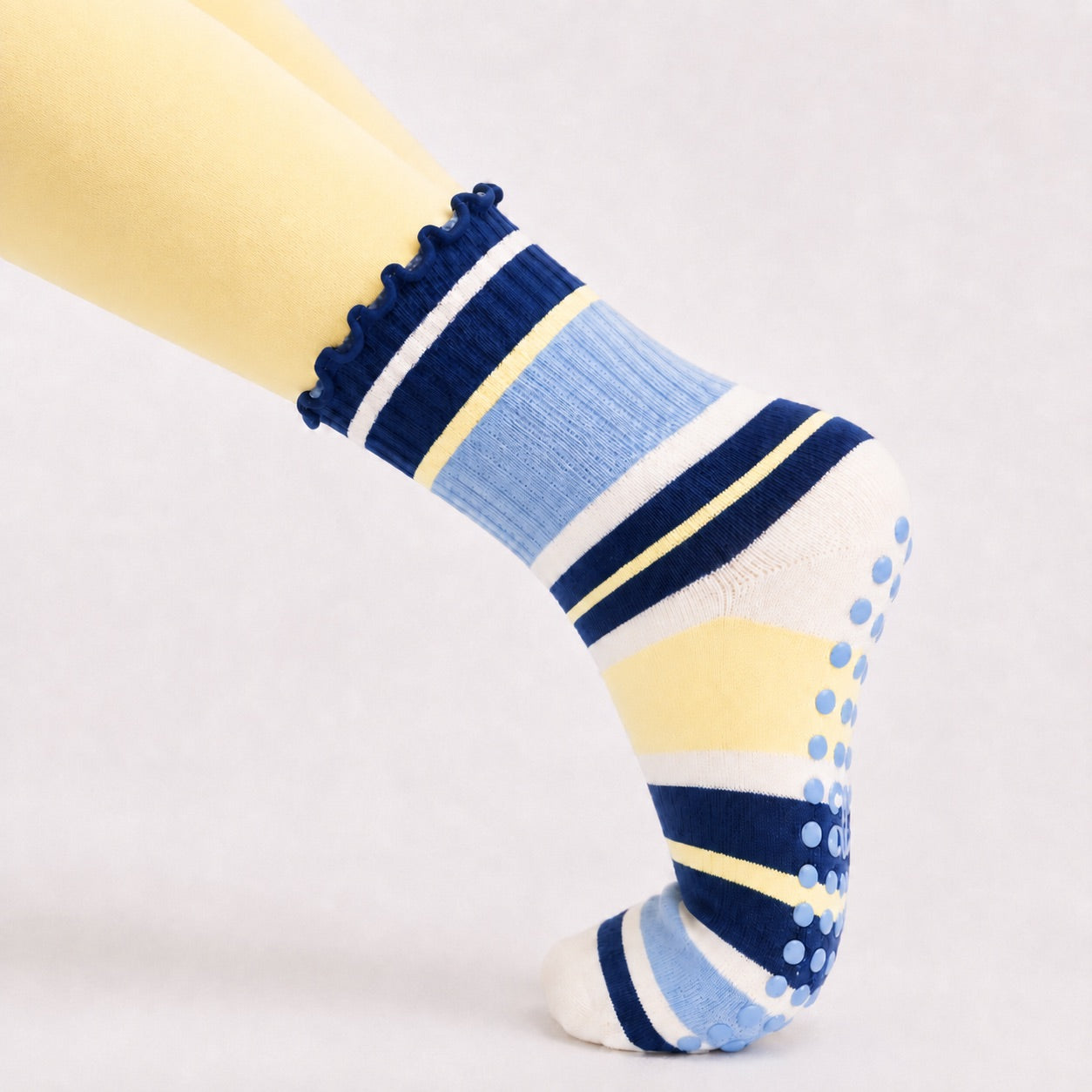 Woman holding a plank in blueberry lemon striped grip socks, close-up of the non-slip sole