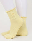 Butter yellow ribbed pilates grip socks worn with white leggings, side view of ruffle cuff
