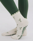 Cream martini print pilates grip socks worn with green leggings, side view of ruffle cuff