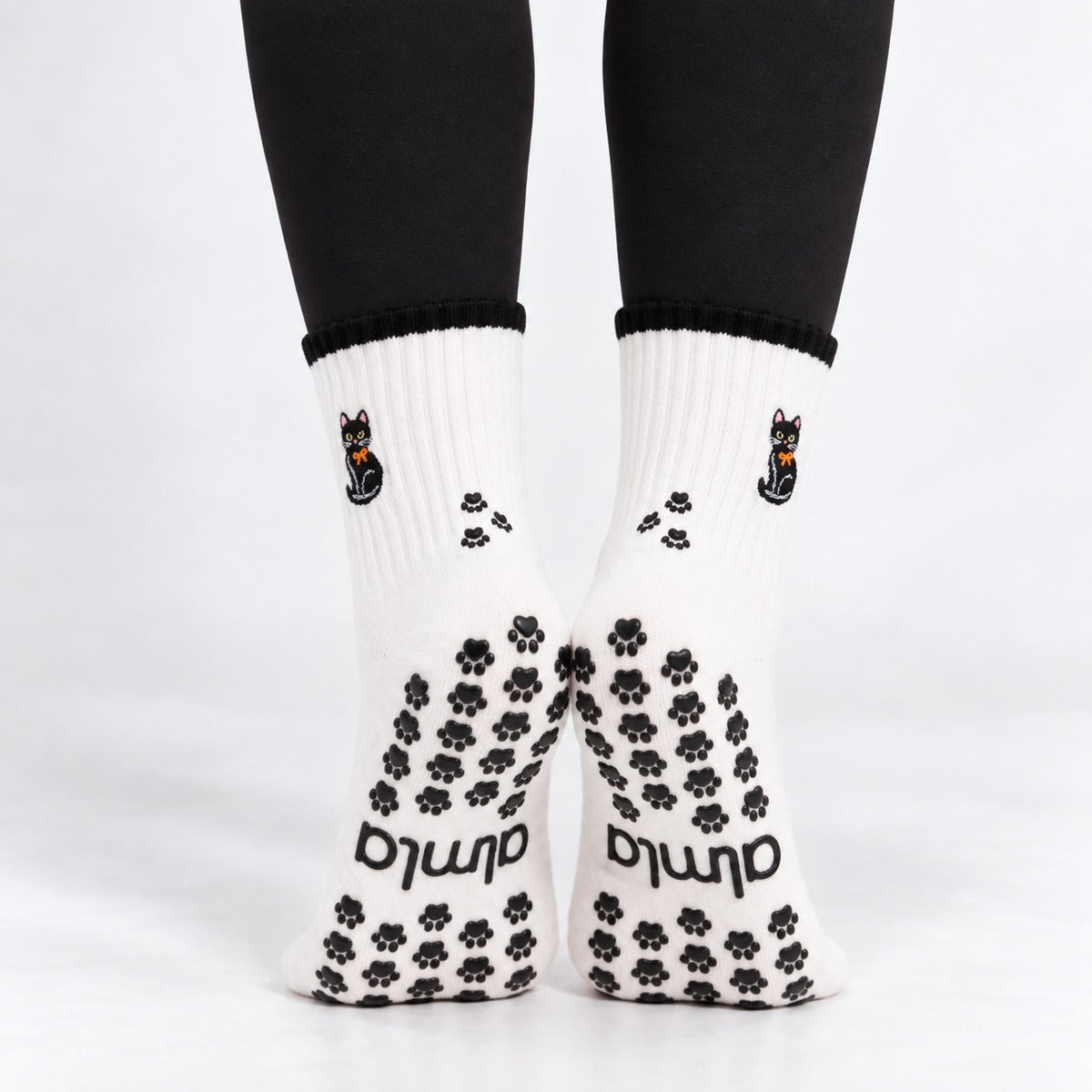 Back view of Black Cat Grip Socks on feet showing black paw print grips, almla logo and paw prints on the ankle