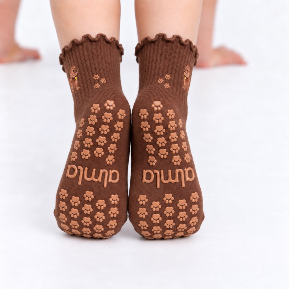 Back view of The Doodle Grip Sock worn on both feet, showing the full paw-print grip pattern and Almla logo on the soles