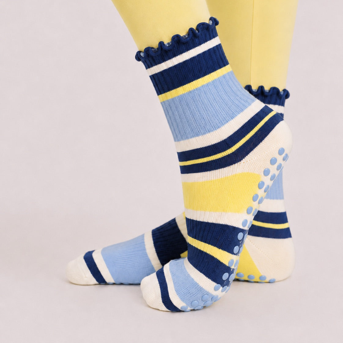 Navy and yellow striped pilates grip socks worn with butter yellow leggings, side view
