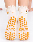Back view of The Orange Cat Grip Sock worn on both feet, showing the full paw-print grip pattern and Almla logo on the soles