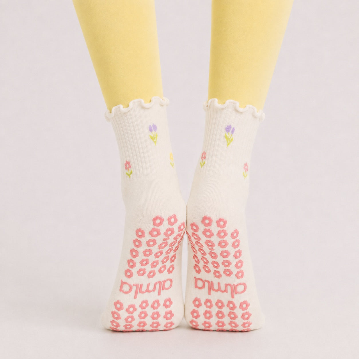Flower print crew grip socks worn with yellow leggings, back view with grip soles showing