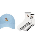The Tri-Color Corgi Set, a washed denim corgi hat with matching oat milk Tri-Color Corgi grip socks with black paw print grips