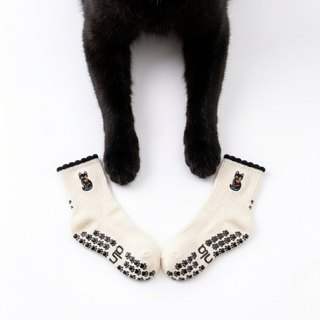 Black cat's front paws resting between a pair of Black Cat Grip Socks