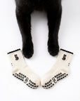 Black cat's front paws resting between a pair of Black Cat Grip Socks