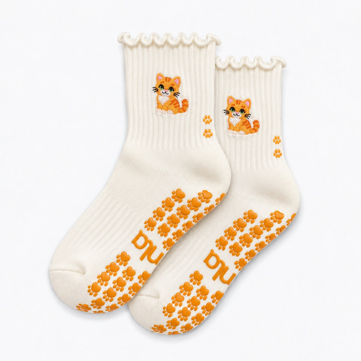 The Orange Cat Grip Sock in cream with an embroidered orange tabby cat, ruffle cuff, and paw-shaped non-slip grips, laid flat on a white background