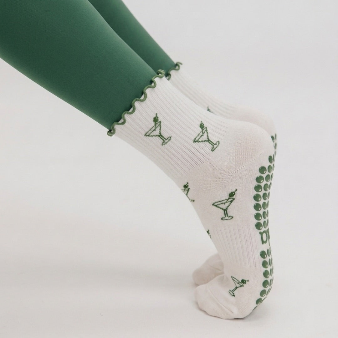 Close-up of a woman in plank wearing martini print grip socks with green grips on the sole