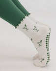 Close-up of a woman in plank wearing martini print grip socks with green grips on the sole