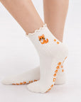 Model wearing The Orange Cat Grip Sock, crossed feet showing the paw-print grip soles and embroidered orange tabby cat on the ruffle cuff
