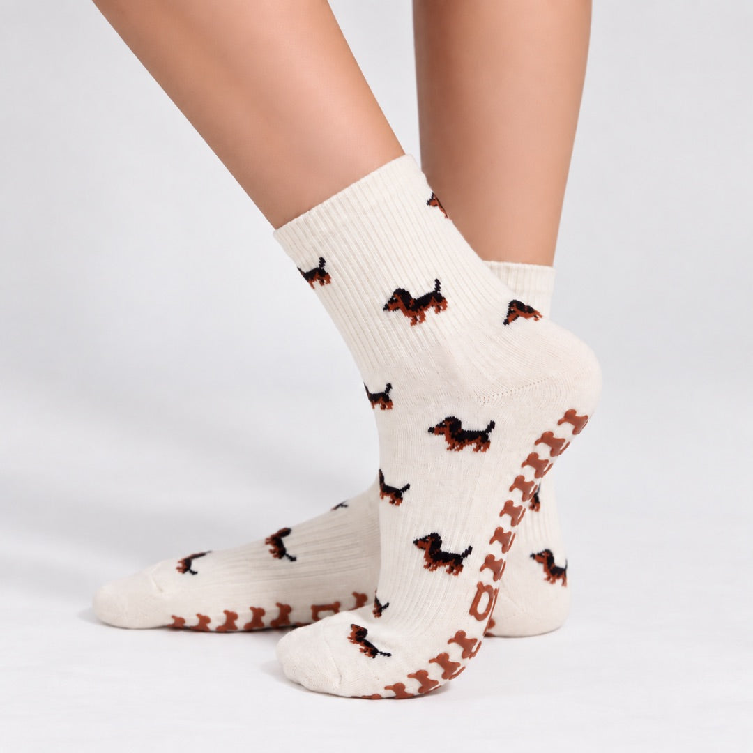Model wearing The Dachshund Grip Sock, crossed feet showing the all-over dachshund print and dachshund-shaped grip soles
