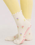 Cream floral pilates grip socks worn with butter yellow leggings, side view of ruffle cuff