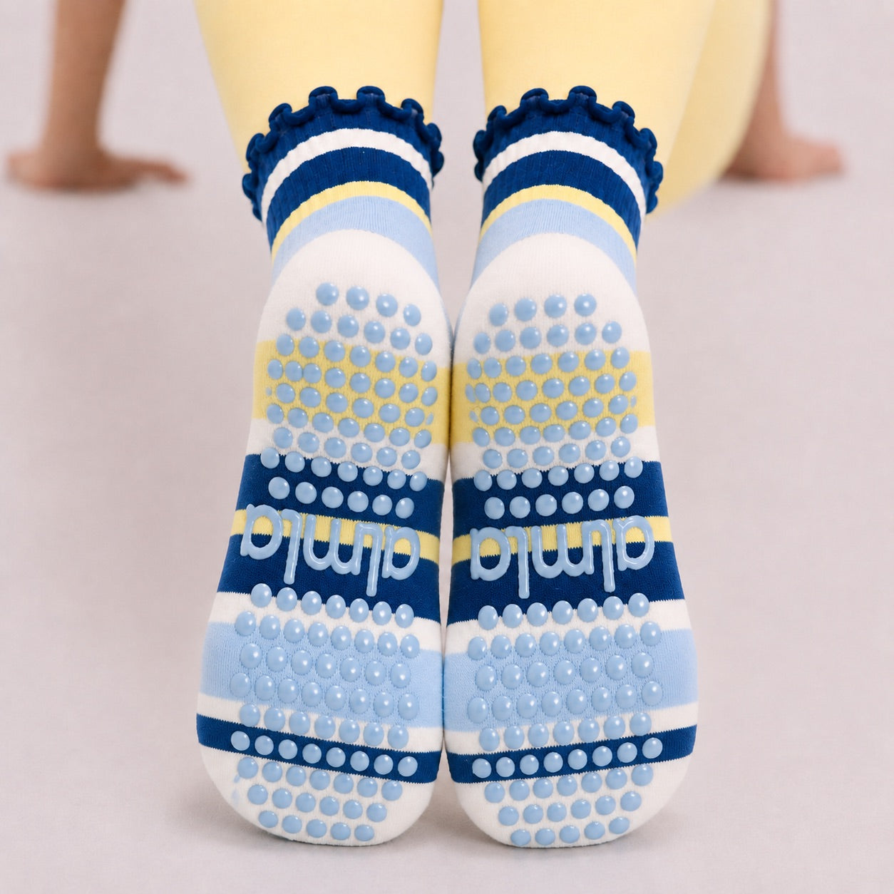 Blue and yellow grip sock soles seen from behind, full grip pad and almla logo visible