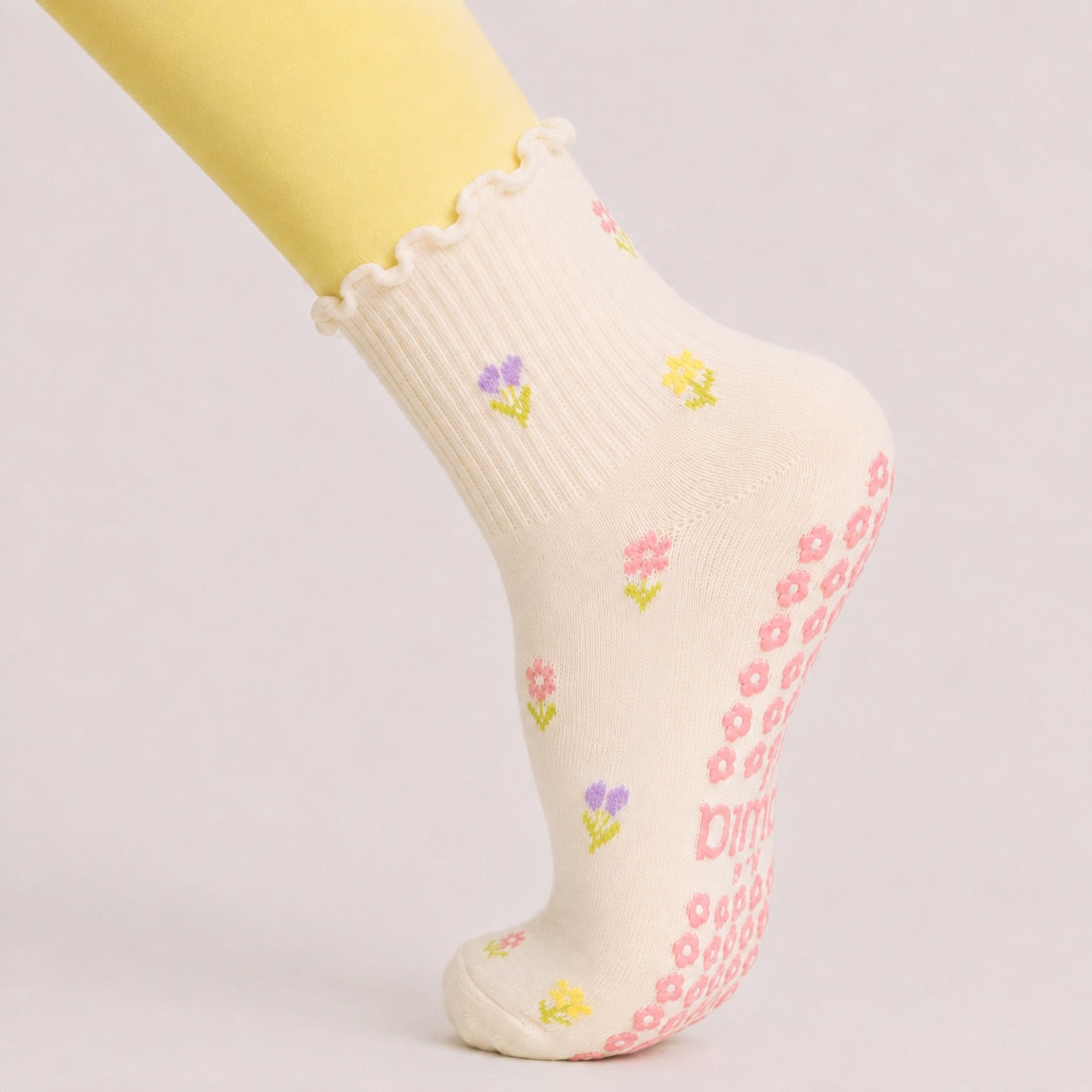 Woman in a plank position wearing floral grip socks, pink flower grips visible on the sole