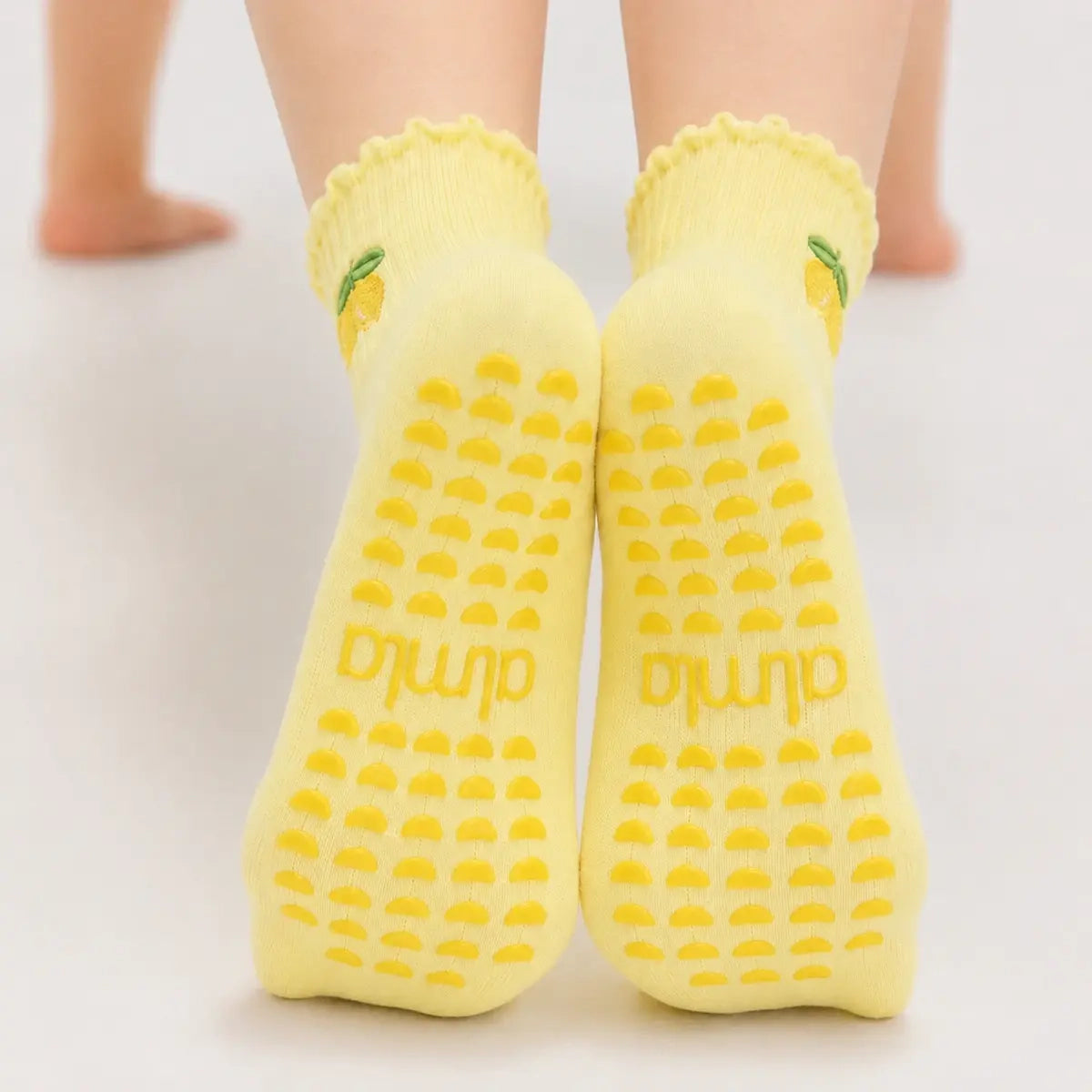 Back view of legs wearing yellow lemon grip socks with textured yellow non slip yoga socks soles.
