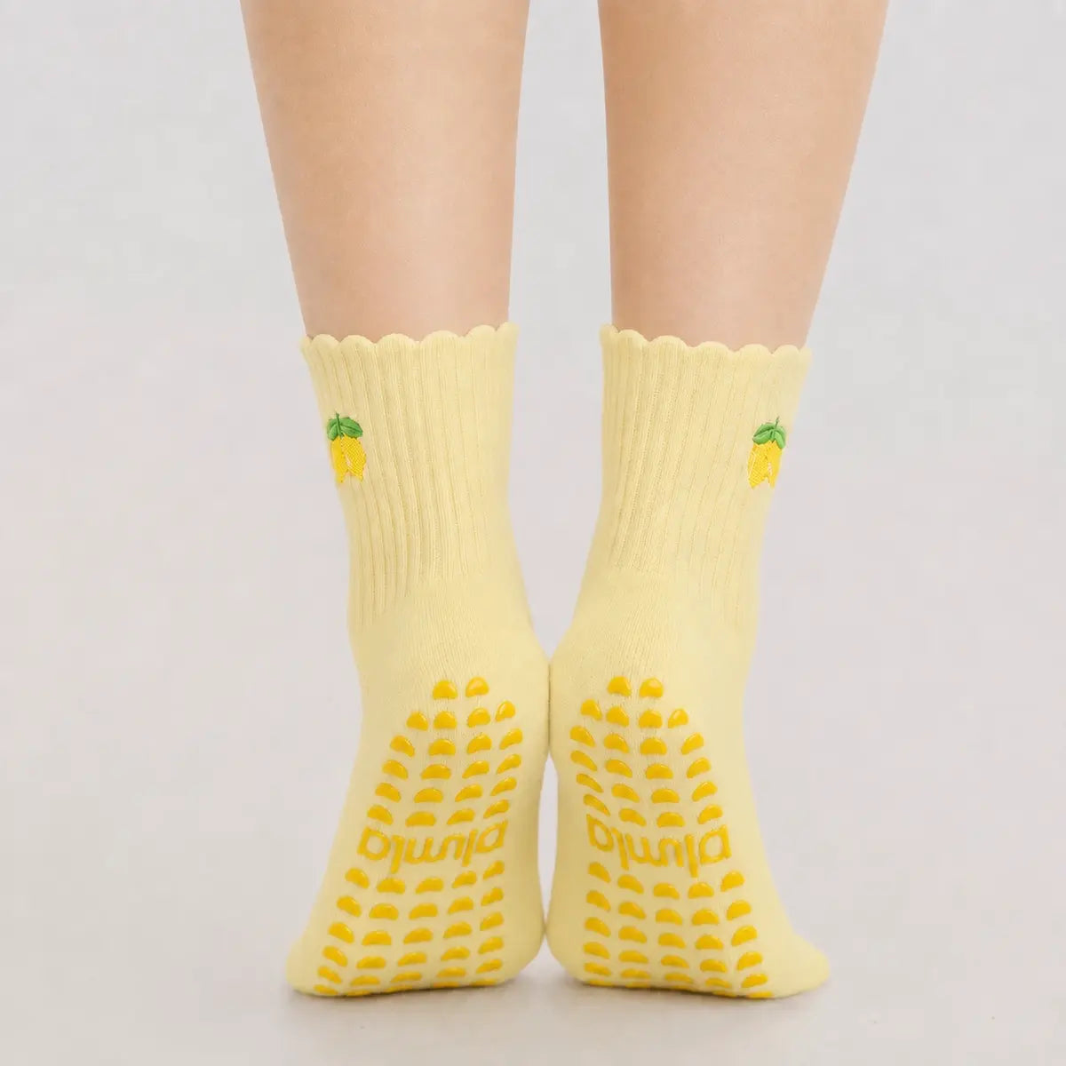 Close-up of bare feet wearing yellow lemon-embroidered socks, showing the best grip socks for pilates sole texture.