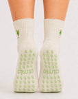 Back view of raised feet wearing cream cocktail-embroidered best grippy socks for barre with green grip dots.