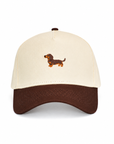 Front view of The Doxie Brown Hat, a cream crown baseball cap with a brown brim and embroidered dachshund