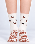 Model standing in a pair of The Dachshund Grip Sock, front view showing the dachshund print and dachshund-shaped grip soles with the Almla logo