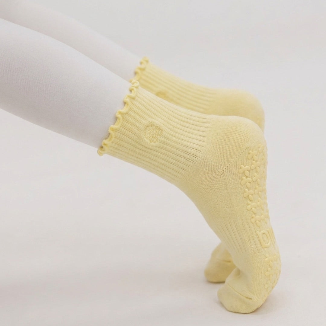 Woman holding a plank in butter yellow grip socks, tonal non-slip grips gripping the mat